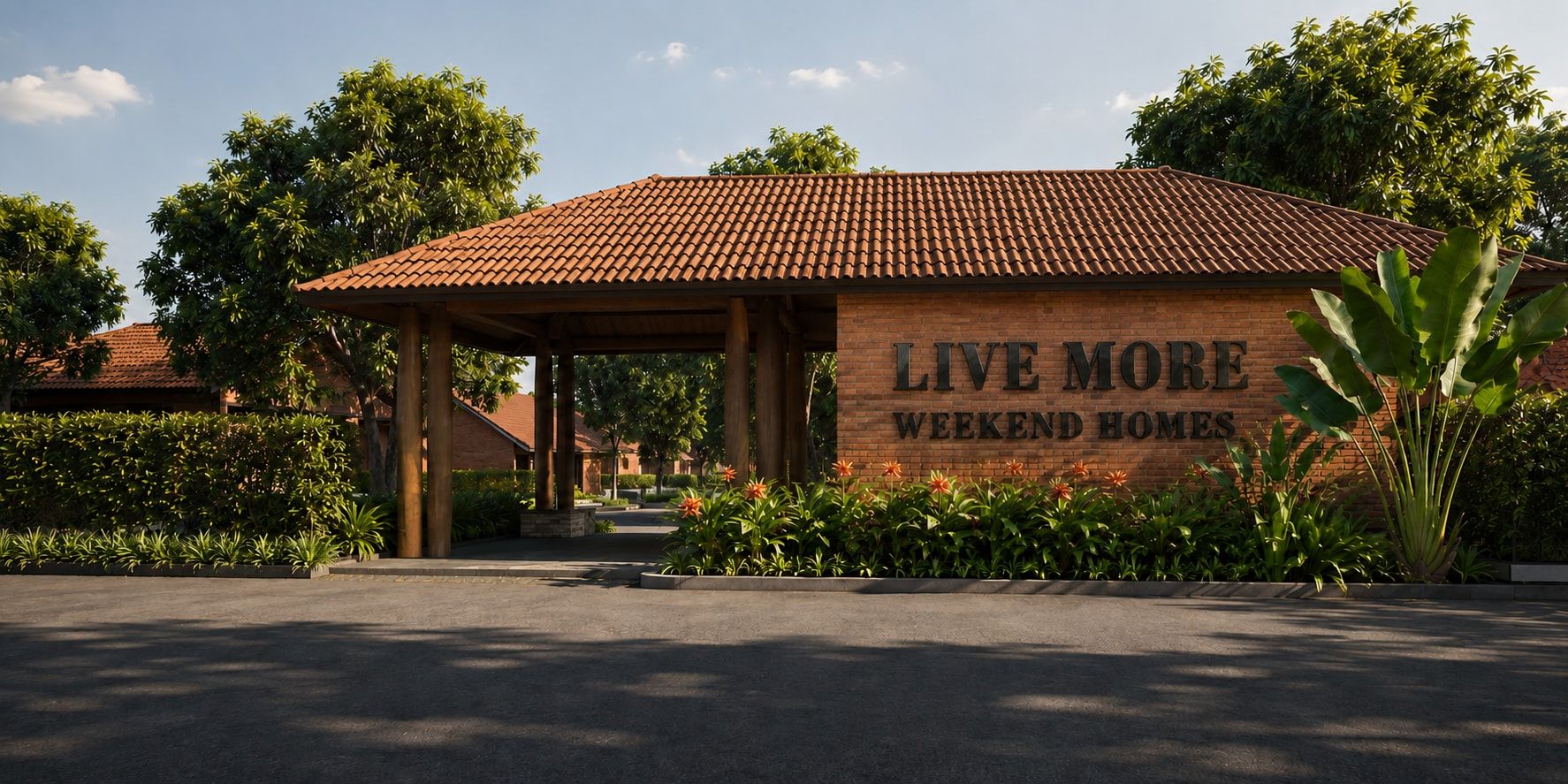 The Live More entrance: a brick pavilion under a tiled roof with the Live More Weekend Homes sign, among mango trees.